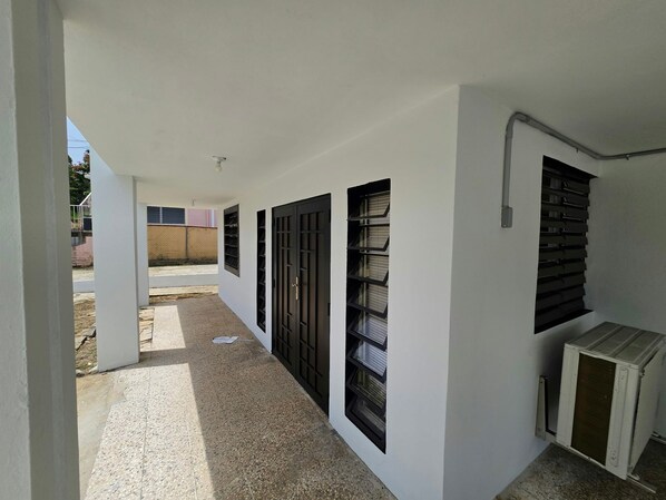 A corridor with multiple black-framed windows and a white air conditioning unit.