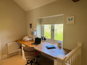 A home office with a desk, chair, laptop, and a window with a view of greenery. - Lakeside Retreat A Romantic Country Escape (Whitchurch)