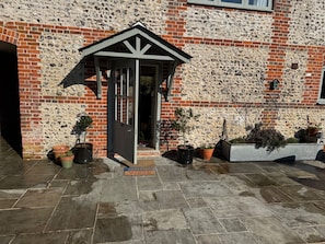 A building entrance with a stone wall, a door, and potted plants. - Lakeside Retreat A Romantic Country Escape (Whitchurch)
