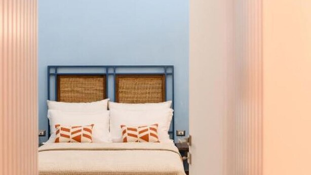 A bed with a headboard, pillows, and a blanket in a room with blue walls. - Nea Santa Monica By Dimorra  (Naples)