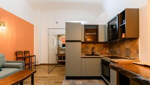A compact living space with a kitchenette, a dining area, and a seating area with a bench. - Nea Santa Monica By Dimorra  (Naples)