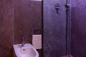 Ein Badezimmer mit einem Standwaschbecken, einem Handtuchhalter und einer Duschkabine.