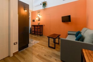 Ein modernes Wohnzimmer mit einer Couch, einem kleinen Tisch und einem an der Wand befestigten Fernseher.