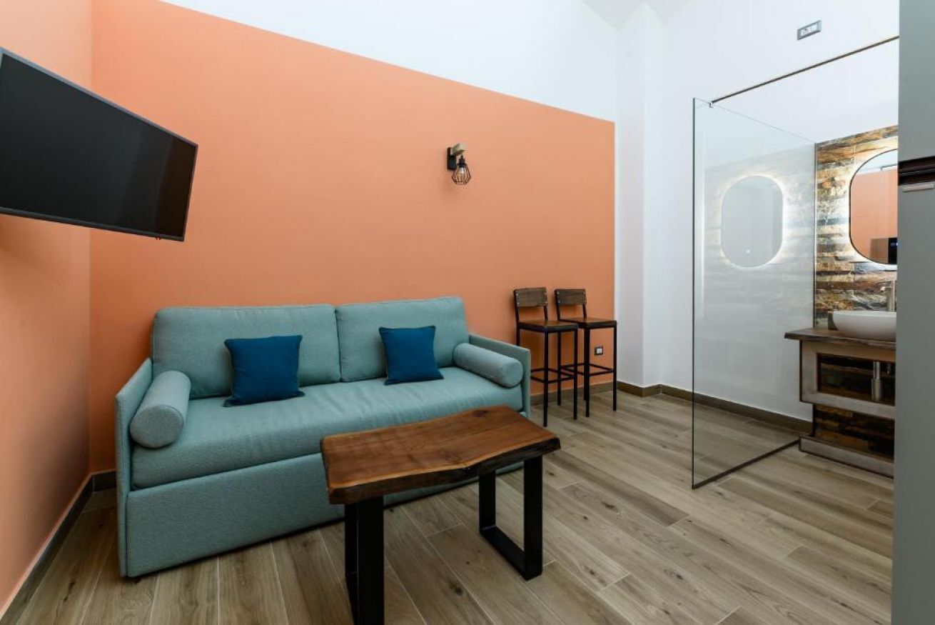 A modern living room with a sofa, a coffee table, and a TV mounted on the wall.