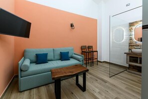 A modern living room with a sofa, a coffee table, and a TV mounted on the wall. - Nea Santa Monica By Dimorra  (Naples)