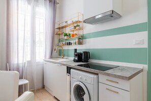 A compact kitchen with a built-in washing machine, a coffee maker, and a shelf with kitchen items. - Casa 3 Frecce a Corte Isolani by Wonderful Italy (Bologna)