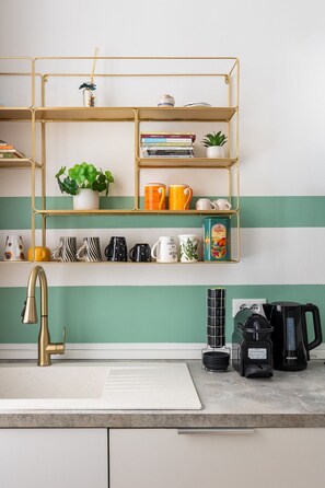 A kitchen with a gold-framed shelf unit, a white sink, a gold faucet, and a coffee maker. - Casa 3 Frecce a Corte Isolani by Wonderful Italy (Bologna)