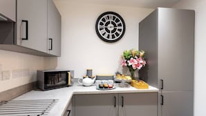 Una cucina moderna con un forno a microonde, un bollitore e una sveglia appesa al muro.