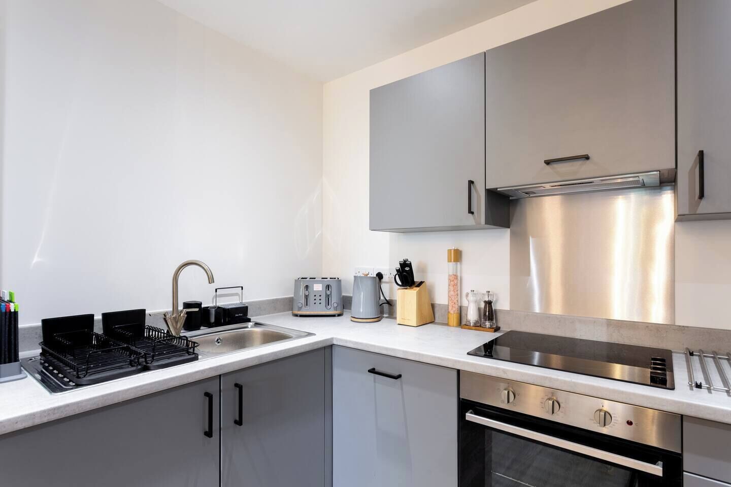 Eine moderne Küche mit einem Edelstahl-Kühlschrank, einem eingebauten Backofen und einem Spülbecken mit Armatur.
