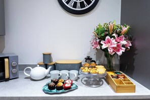 A kitchen counter with a teapot, cups, a coffee pot, and a variety of pastries and cookies. - #57 Central Taunton 2BR APT - Sleeps 6 - 5 mins to Taunton Player Ready 2 (Somerset)