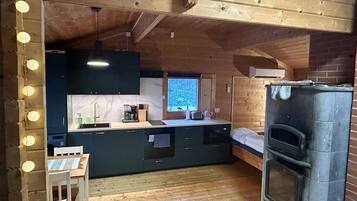 Una cocina compacta con horno integrado, piso de madera y ventana con vista a la vegetación.