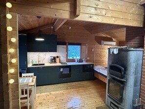 A compact kitchen with a built-in oven, wooden flooring, and a window overlooking greenery.