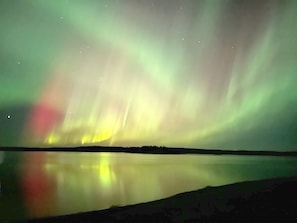 A calm body of water reflecting the Northern Lights.