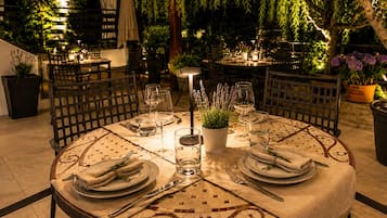 Un espacio de comedor al aire libre con mesas redondas, sillas y plantas en macetas.