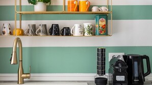 A kitchen with a gold-framed shelf unit, a white sink, a gold faucet, and a coffee maker. - Casa 3 Frecce a Corte Isolani by Wonderful Italy (Bologna)