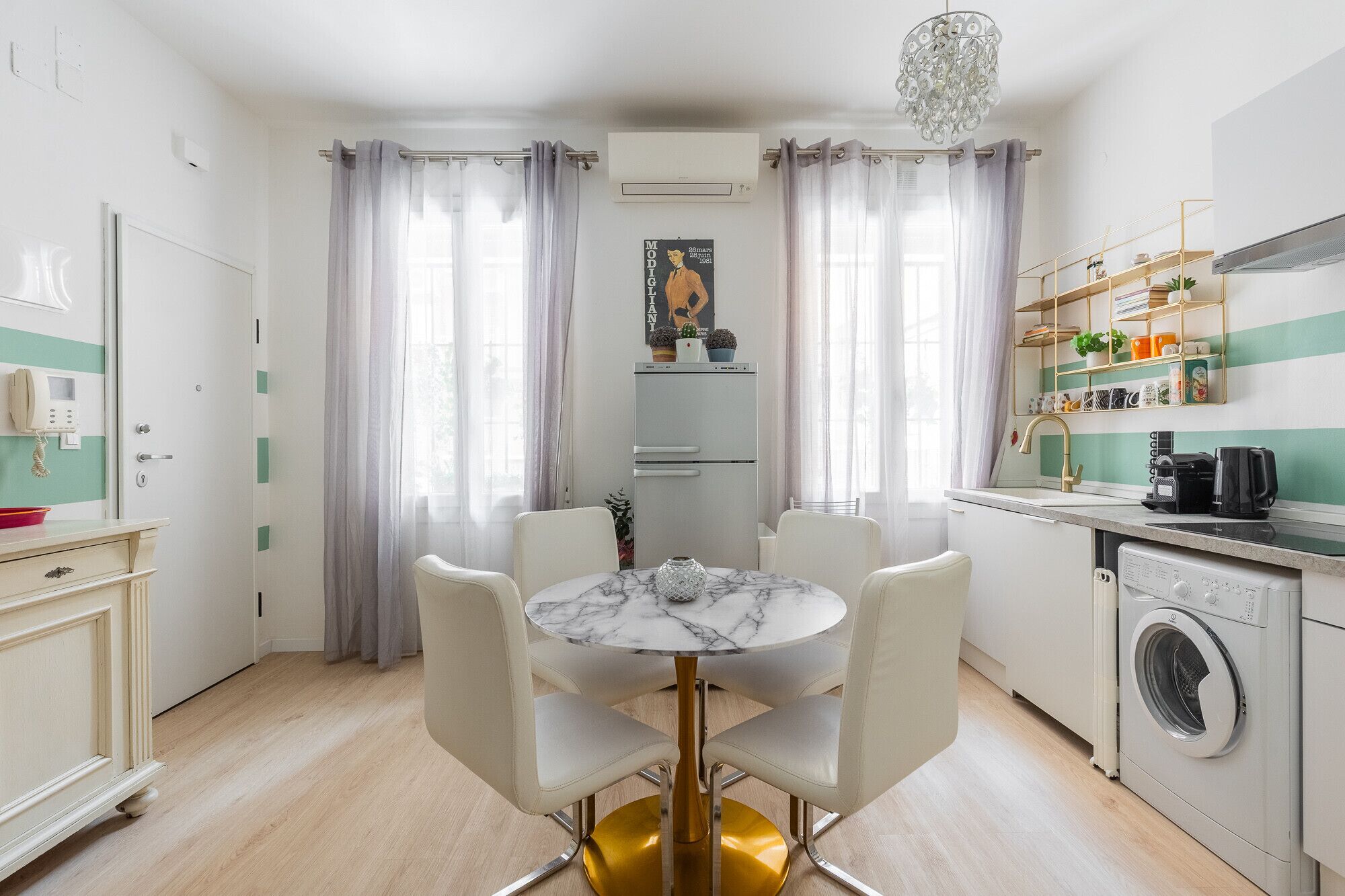 A compact kitchen with a built-in washing machine, a dining area with a marble table, and a small refrigerator.