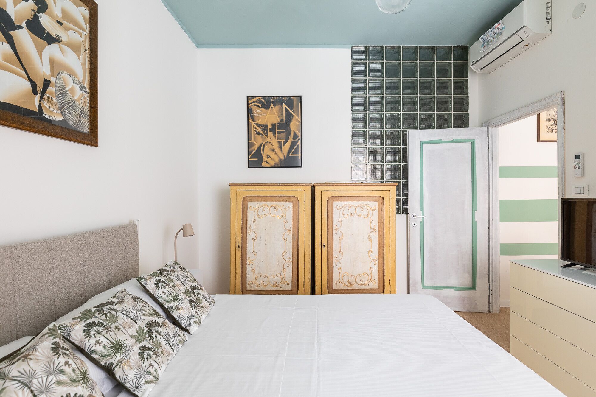Een slaapkamer met een bed, een garderobe, een deur en een wandairconditioner.