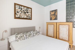 Ein Schlafzimmer mit einem Bett, zwei Nachttischen, einer Kommode und Wandbildern.