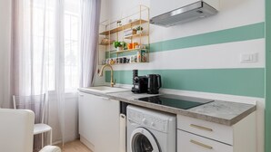 A compact kitchen with a built-in washing machine, a coffee maker, and a shelf with kitchen items. - Casa 3 Frecce a Corte Isolani by Wonderful Italy (Bologna)