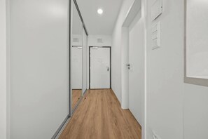 A corridor with a wooden floor, white walls, and a door at the end. - AC 1 room Apartment, Hranicna street (Bratislava)