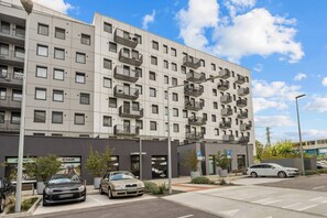 A multi-story residential building with balconies, a parking area, and a visible storefront. - AC 1 room Apartment, Hranicna street (Bratislava)