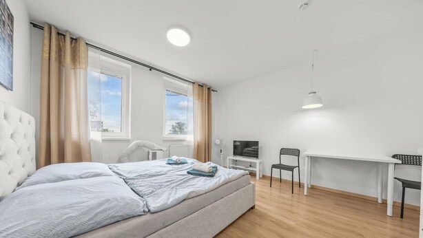 Ein modernes Schlafzimmer mit einem großen Bett, einem Schreibtisch, einem Stuhl und einem Fernseher.
