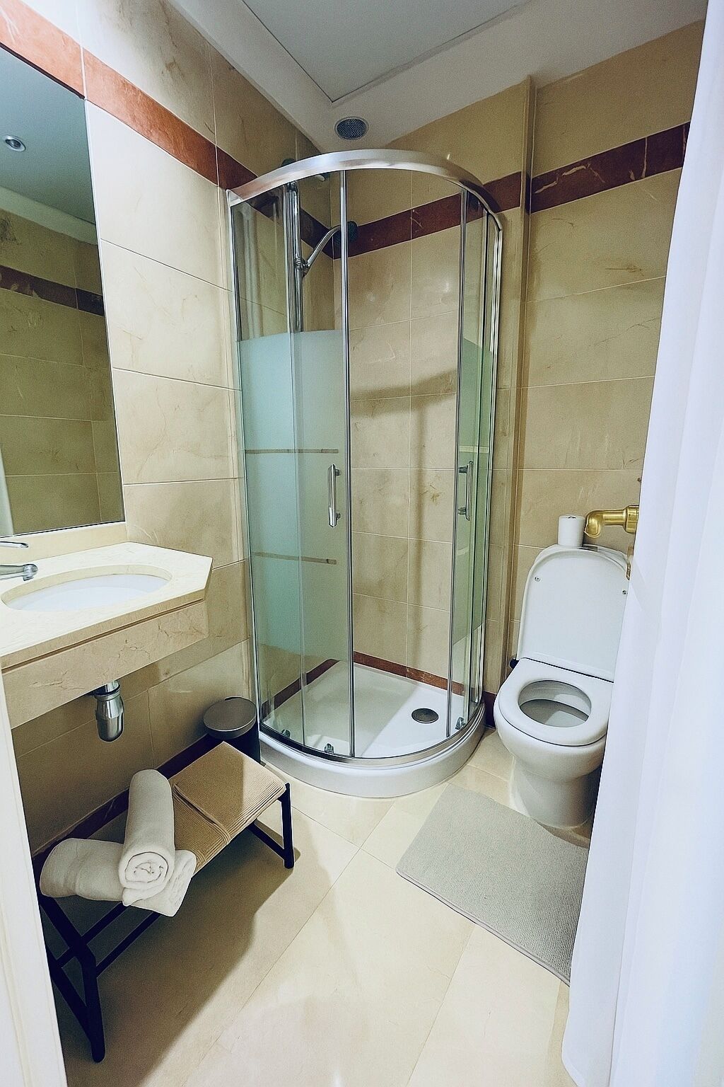 A bathroom with a glass-enclosed shower, a toilet, and a sink.