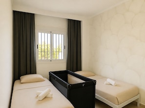 Ein Hotelzimmer mit zwei Betten, einem Fenster mit Vorhängen und einer Wand mit Muster.