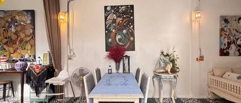 A dining area with a table set for four, surrounded by chairs, with a decorative vase and a wall-mounted painting above.