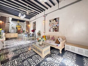 A room with a patterned floor, a sofa with cushions, a coffee table, and a painting on the wall.