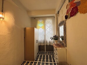 A narrow hallway with a patterned floor, a door, and a window with a geometric pattern. - A colorful Bohemian retreat with unique design and cozy vibes. Good location (Chang Wat Chiang Mai)