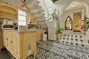 A kitchen with a central island, a washing machine, and a refrigerator. - A colorful Bohemian retreat with unique design and cozy vibes. Good location (Chang Wat Chiang Mai)