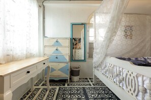 A room with a bed, a dresser, a mirror, and a patterned floor.