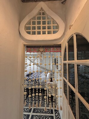 A room with a bed, a decorative window, and a patterned floor. - A colorful Bohemian retreat with unique design and cozy vibes. Good location (Chang Wat Chiang Mai)