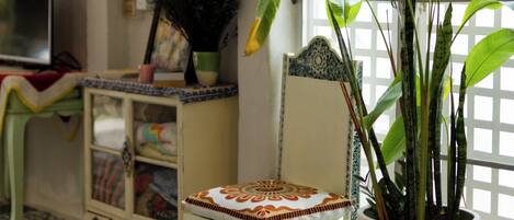 Una habitación con piso estampado, una planta en maceta, una silla decorativa y obras de arte en la pared.