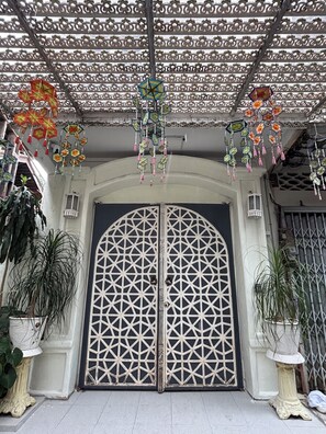 A traditional gate with intricate lattice design, flanked by potted plants, and hanging decorative items. - A colorful Bohemian retreat with unique design and cozy vibes. Good location (Chang Wat Chiang Mai)