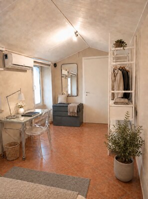A compact room with a desk, chair, and a wardrobe.