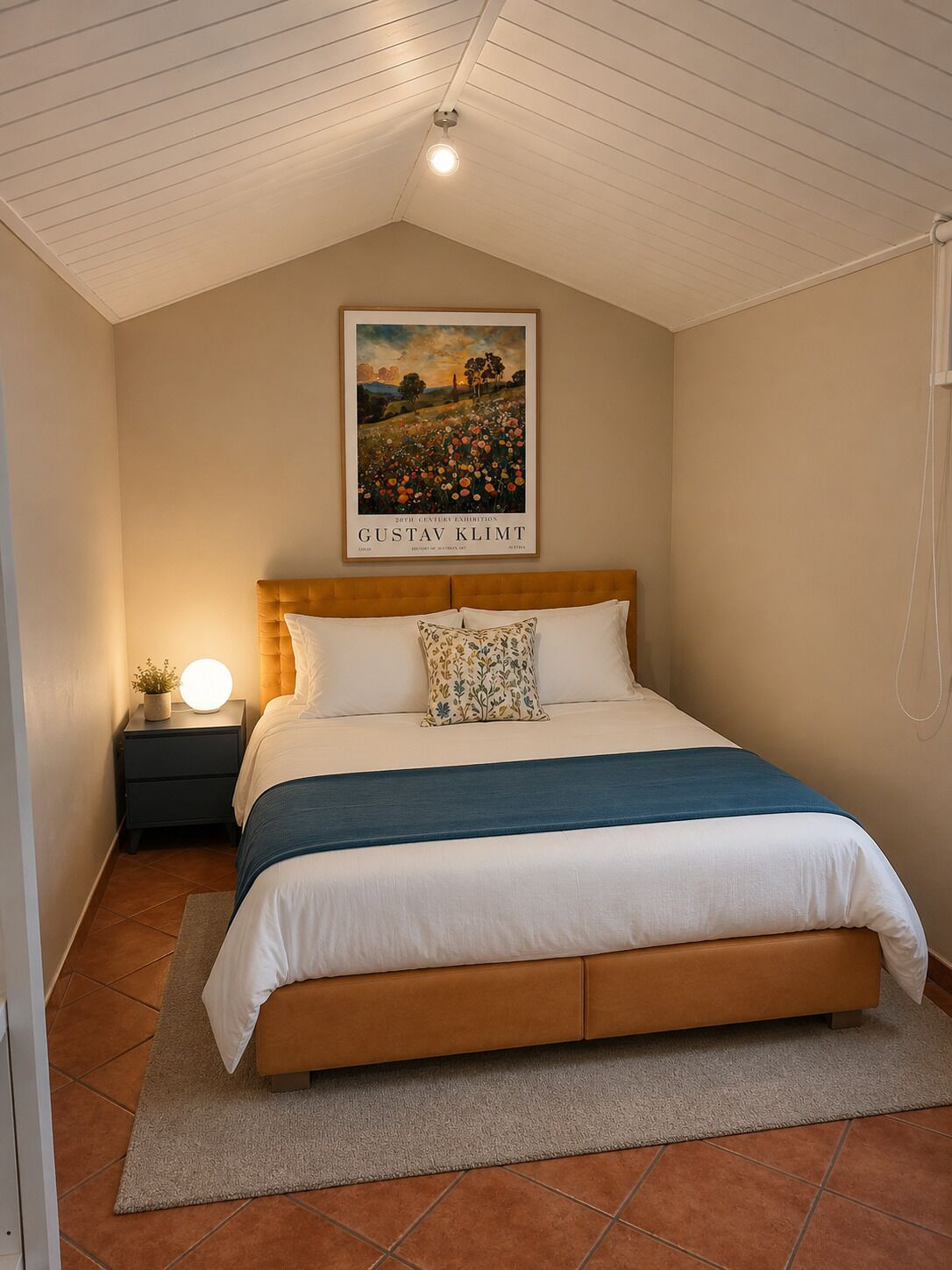 Un dormitorio con cama, mesita de noche, lámpara y un cuadro en la pared.