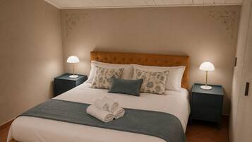 A neatly made bed with a headboard, two bedside tables with lamps, and a folded towel on the bed.