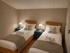 A twin room with two beds, each with a nightstand, lamps, and decorative pillows.