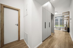Ein Flur mit einer Holztür, einer weißen Wand und einem grauen Kleiderschrank.