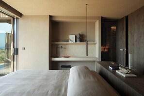 Ein modernes Schlafzimmer mit einem großen Bett, einer eingebauten Ablagefläche mit Dekoration und Blick ins Freie.