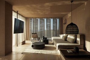 Ein modernes Wohnzimmer mit einer Couch, einem Couchtisch, einem Fernseher und einem großen Fenster mit Vorhängen.