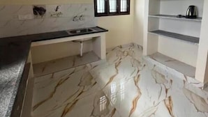A kitchen with marble flooring, a window, and built-in shelves.