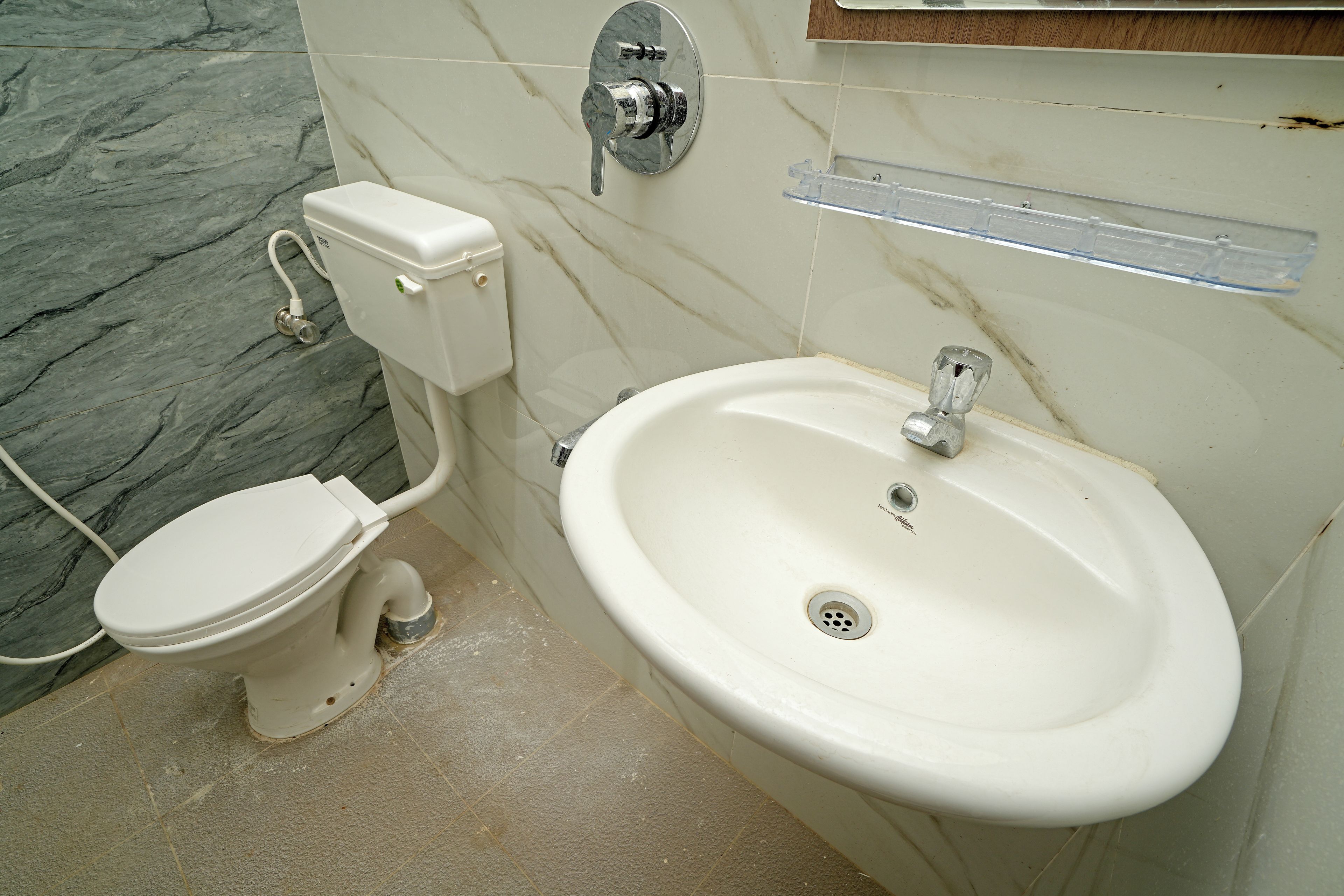 Un baño con inodoro, lavamanos y pared de mármol.