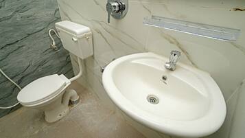 Une salle de bain avec des toilettes, un lavabo et un mur en marbre.