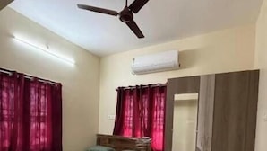 A bedroom with a bed, a ceiling fan, an air conditioning unit, and a marble floor.