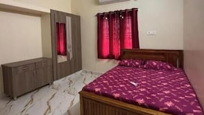 A bedroom with a bed, a wardrobe, a ceiling fan, and a window with curtains.