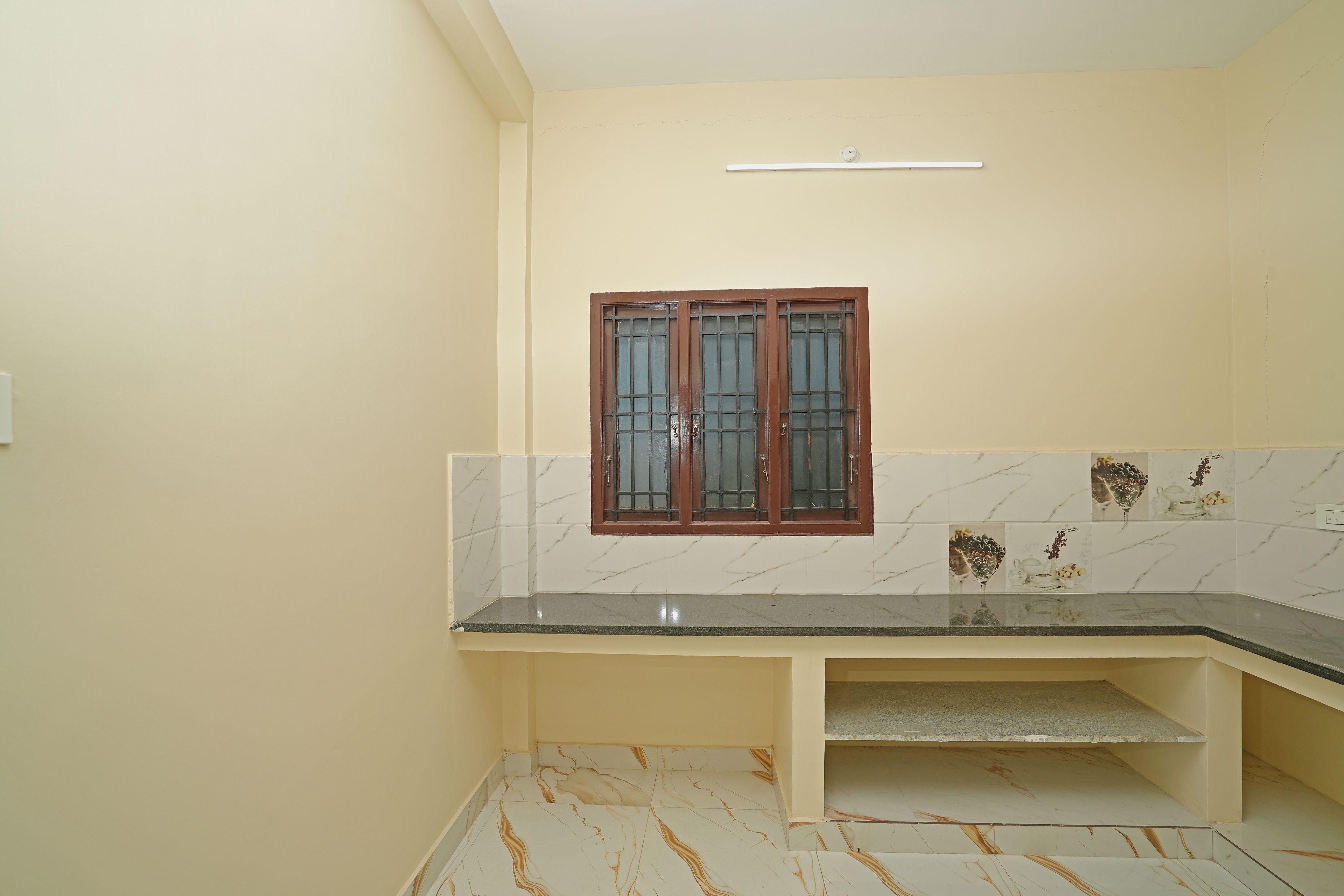 A bathroom with a marble-tiled wall, a black countertop, and a window with a wooden frame.
