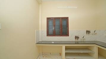 A bathroom with a marble-tiled wall, a black countertop, and a window with a wooden frame.
